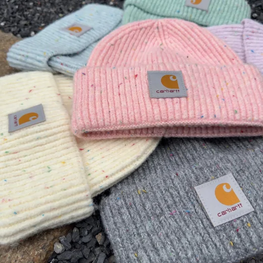 Group of speckled knit beanies in pink, grey and cream with small square patches