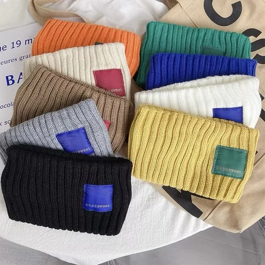 Pile of ribbed knit beanies in black, cream, blue, yellow and green