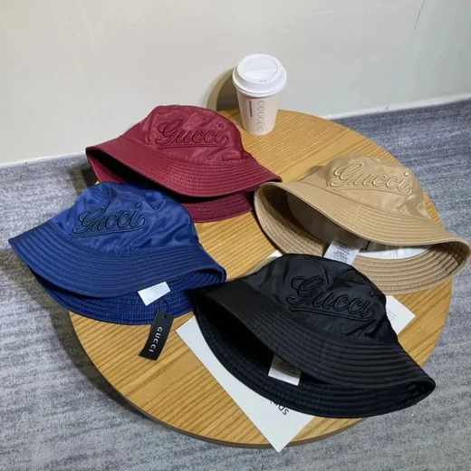 Bucket hats in burgundy, royal blue, black and tan arranged on a round wooden board