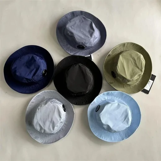 Six bucket hats in navy, grey, black, olive and pale blue laid out in a circle