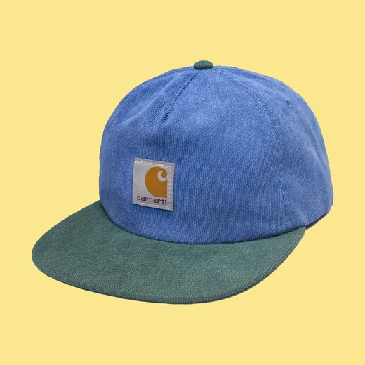 Blue cap with a dark green brim and a small square patch on a yellow background