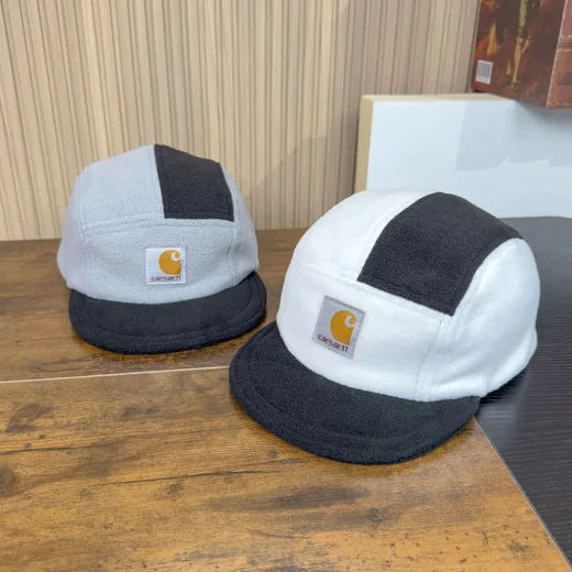 Two colour-block five-panel caps on a wooden table, one white with black, one pale blue with navy
