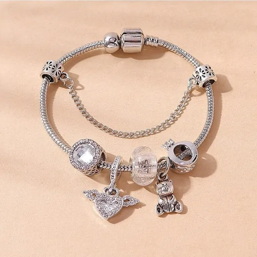 Silver snake-chain bracelet with clear beads, a bear charm and a winged heart charm