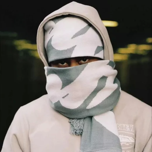 Person wearing a grey camouflage knit scarf wrapped up to the eyes