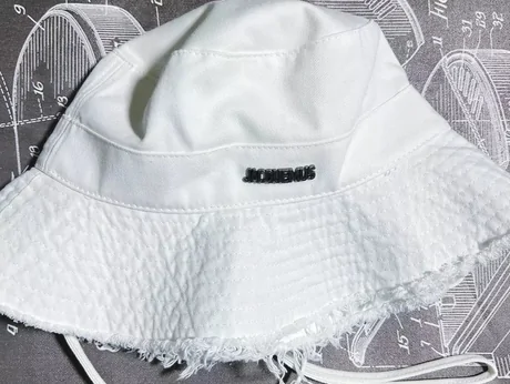 White canvas bucket hat with a heavily frayed brim and a woven label