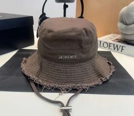 Brown wide-brim bucket hat with a frayed edge and a chin cord on a stand