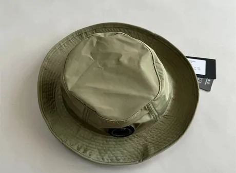 Olive green nylon bucket hat lying on a pale surface