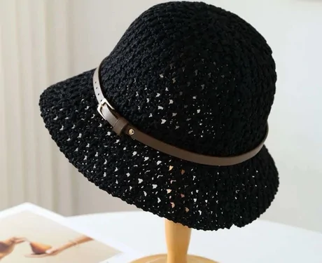 Black open-crochet bucket hat with a thin brown belt band on a wooden stand
