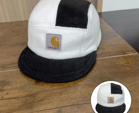 White and black colour-block cap on a table with a small round inset photo of its back