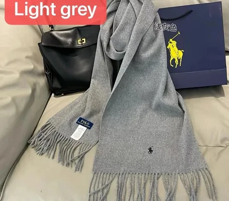 Light grey fringed scarf beside a black handbag and a paper bag