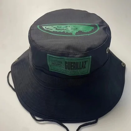 Black bucket hat with a green printed patch and a chin cord