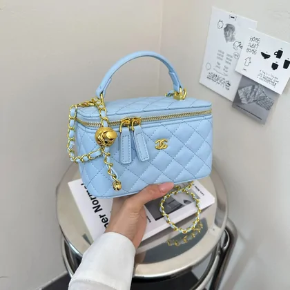 Hand holding a pale blue quilted bag with gold-tone hardware